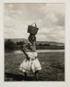 [Woman carrying basket on head]