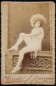 [Female performer with afro posed on a ledge]