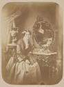 [Young woman, seated in room with mirror]