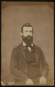 [Man with dark hair and full beard, seated]