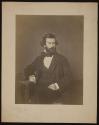 [Bearded man, seated, looking to his left.]