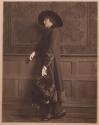 [Standing woman wearing hat and coat]