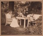 [Woman, man and three boys seated in garden]