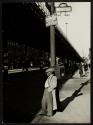 [Man standing under lamppost, corner of 8th Avenue and W. 127th St., Harlem]