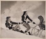 [Two models with elf suits and antlers pulling on sleigh]