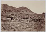 [Group of men outside a log cabin in front of a mountain]