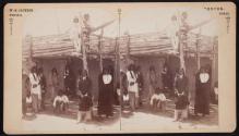 [Group of native Americans in front of adobe house]