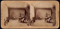 [View of interior of photographic studio, includes woman at retouching easel]
