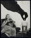[woman dropping pill into glass of water]