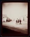 [Three men walking through a town]