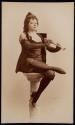 [Woman in costume sitting on a pedestal, holding a recorder]