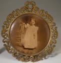 [Small girl in white gown beside ornate posing chair]