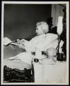 [Mark Twain, propped up in bed, writing]