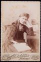 [Girl seated with a stereoviewer and an open book]