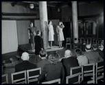 [Fashion models on dais in front of audience]
