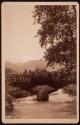 [Bridge over river with mountains in background]