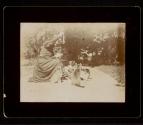 [Woman playing with cats in yard]