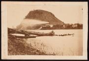 [Tree fallen into water and man in canoe with Barn Bluff in background, Minnesota]