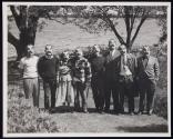 [Group of seven men and one woman, all wearing rubber "Victor Keppler" masks]