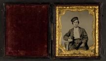 [Young man seated with cap cocked on his head]
