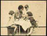 [Woman (model Ruth Malcomson) with three young children, eating at a table]
