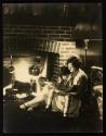 [Woman (model Ruth Malcomson) reading a book to young girl by fireside]