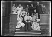 [Group of 11 people with minister on front porch]