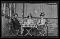 [Dr. Ernest Wilkens and two women, outdoors with coffee and wine]