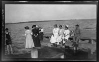 [Group on docks looking into water, includes dalmatian dog]