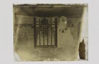 [Woman standing next to headstone]