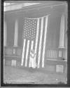 [Child standing by porch with American flag displayed]