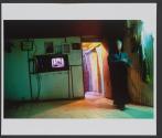 A man walks by a tv broadcasting a prayer, in the unrecognized Bedouin village of El Ukbi