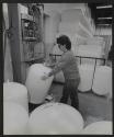 [Worker drilling hole into the spout of a plastic tank.]
