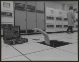[Worker reaching for tools from under the floor in a computer lab]