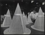 [Technician measuring metal mesh cone at production facility]