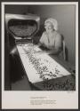 [Worker inspects empty gelatin capsules]