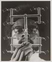 [Technician holding plastic components still attached to sprue in front of his face]