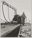 [Worker driving rail road spikes with a pneumatic hammer]