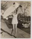 [Model on a street holds a molded Austin Mini front end body panel over her head]