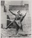 [Ballet dancer posing with construction worker on work site]