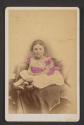 [Child seated on covered chair (or someone's lap)]
