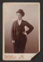 [Young woman posing in man's suit and derby hat]