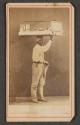 [Man carrying wares on head]