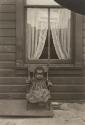 [Child sitting in chair in front of window of Temporary Home]