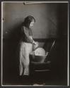 [Girl washing dishes in basin]