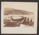[Small wooden ship on land overlooking harbor]