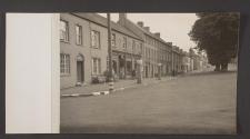 [View of wide residential street with people in doorways]
