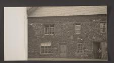 [Young boy in the doorway of a stone rowhouse]