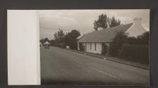 [Whited washed stone buildings with thatched roofs at edge of motorway]