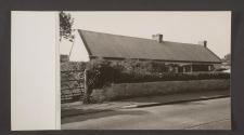 [White stone house with hedge and stone wall]